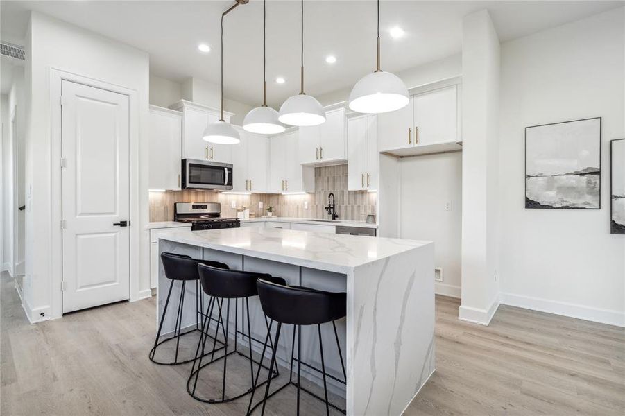 An oversized 7-foot quartz waterfall island commands attention in this culinary haven, paired with a stunning backsplash that adds a touch of glamour to every meal. The perfect blend of style and functionality for the heart of your home.