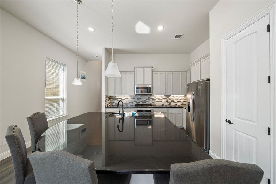 Kitchen with tasteful backsplash, decorative light fixtures, stainless steel appliances, dark hardwood / wood-style flooring, and sink