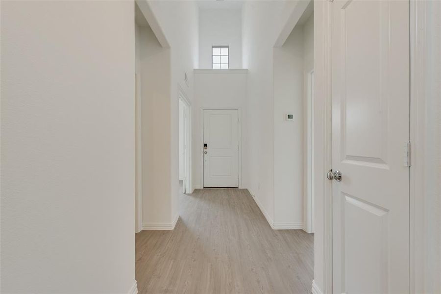 Hallway with a high ceiling and light hardwood / wood-style flooring