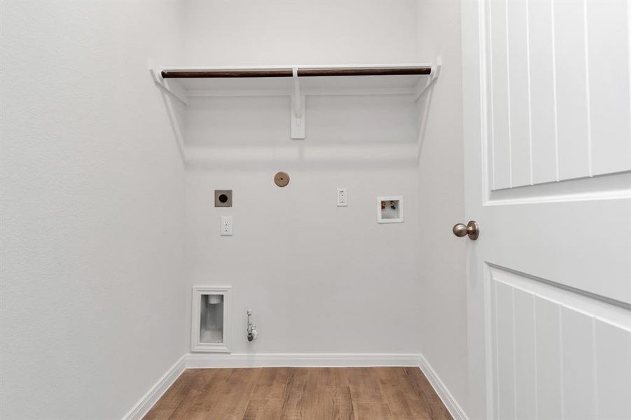 Functional laundry room equipped with all necessary hookups for washer and dryer installation. Simplify your laundry routine in this well-organized space with a built-in shelf for storage. **This image is from another Saratoga Home - Clover floorplan.**