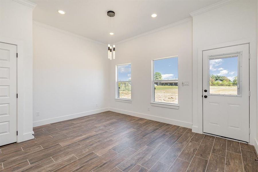 Empty room with ornamental molding, plenty of natural light, and dark wood-type flooring