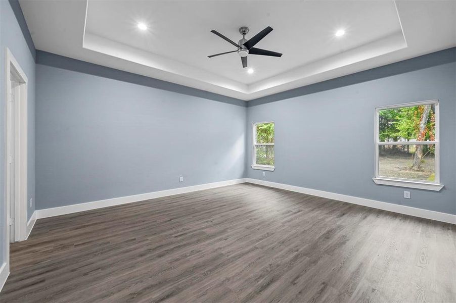 Unfurnished room with ceiling fan, a tray ceiling, and dark hardwood / wood-style flooring