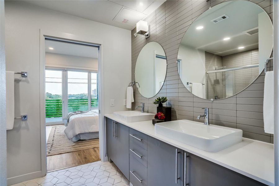 Double vanities in the full bath allows for ample space for two people. Walk in shower is large with modern tile from floor to ceiling.