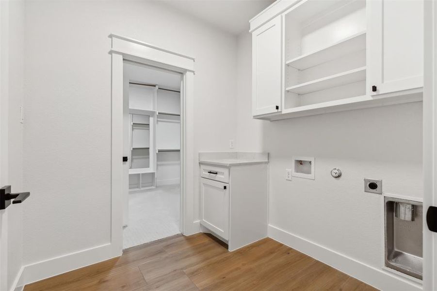 Clothes washing area featuring light hardwood / wood-style flooring, cabinets, electric dryer hookup, and washer hookup