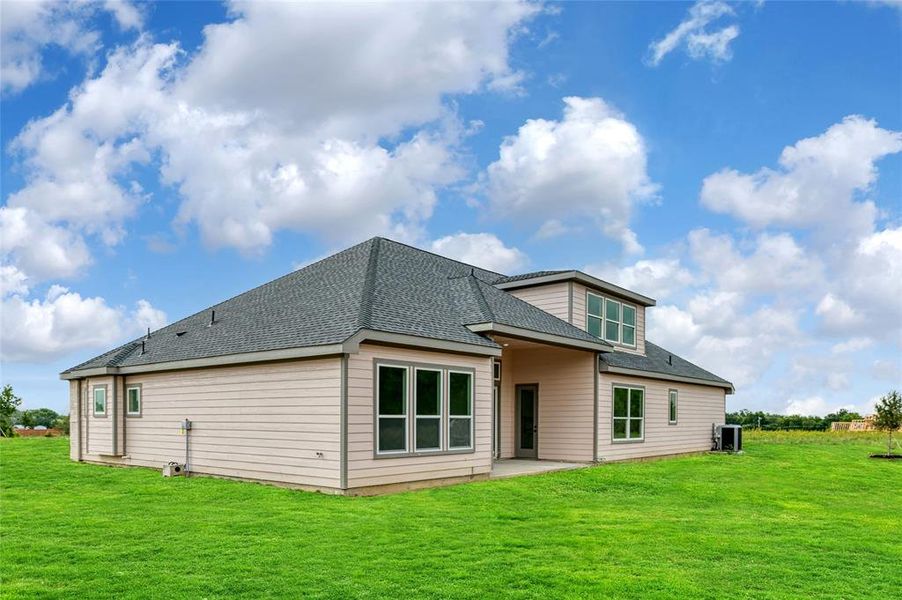 Back of house featuring cooling unit, a lawn, and a patio