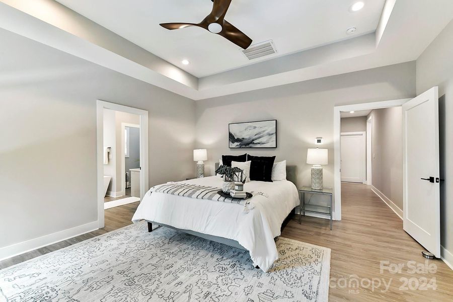 Spacious Primary Bedroom on main level with tray ceiling, recessed lighting, ceiling fan/light, private bath, customized, walk in closet, large windows for Water views & LVP flooring!