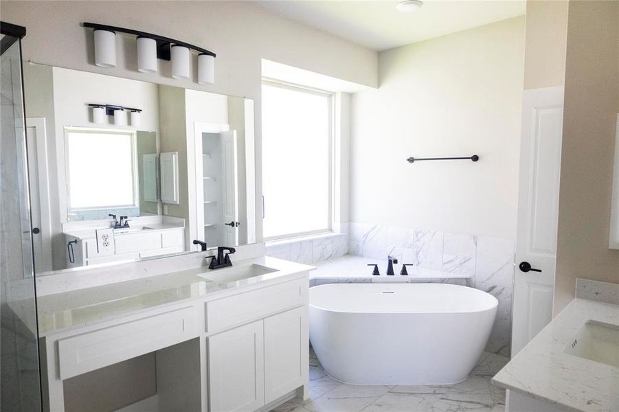 Bathroom with tile patterned floors, a washtub, and double vanity