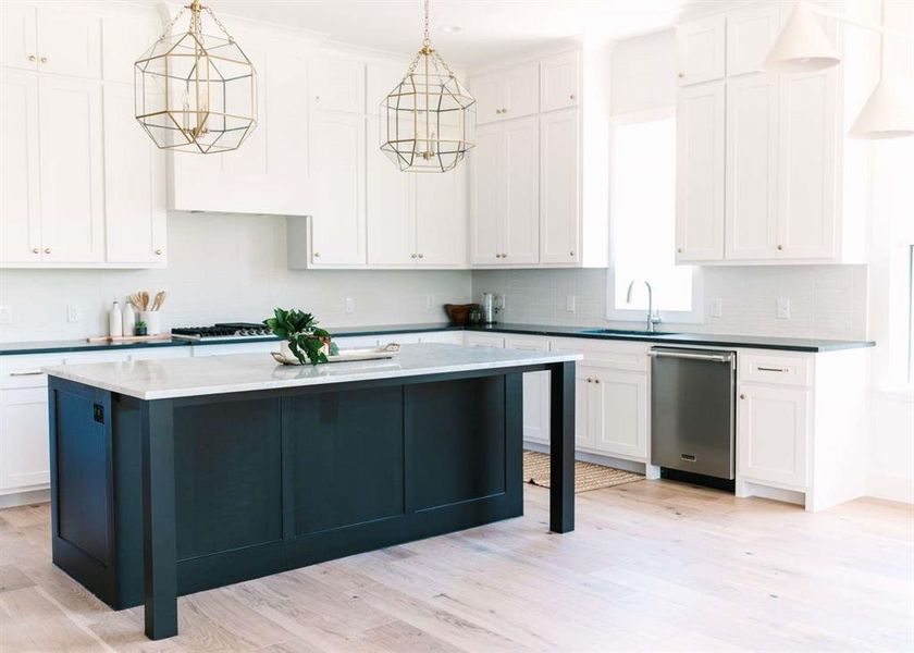 Kitchen featuring hanging light fixtures, a kitchen island, stainless steel appliances, light hardwood / wood-style flooring, and a notable chandelier