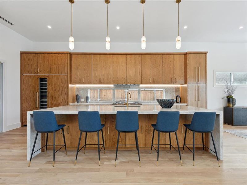 Kitchen featuring decorative light fixtures, a spacious island, and light hardwood / wood-style flooring