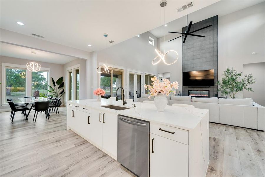 Kitchen with white cabinetry, a center island with sink, dishwasher, and sink