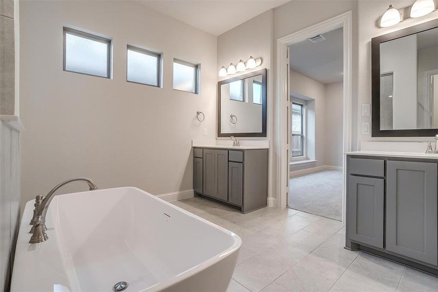 Bathroom featuring tile patterned floors, a tub to relax in, and dual bowl vanity