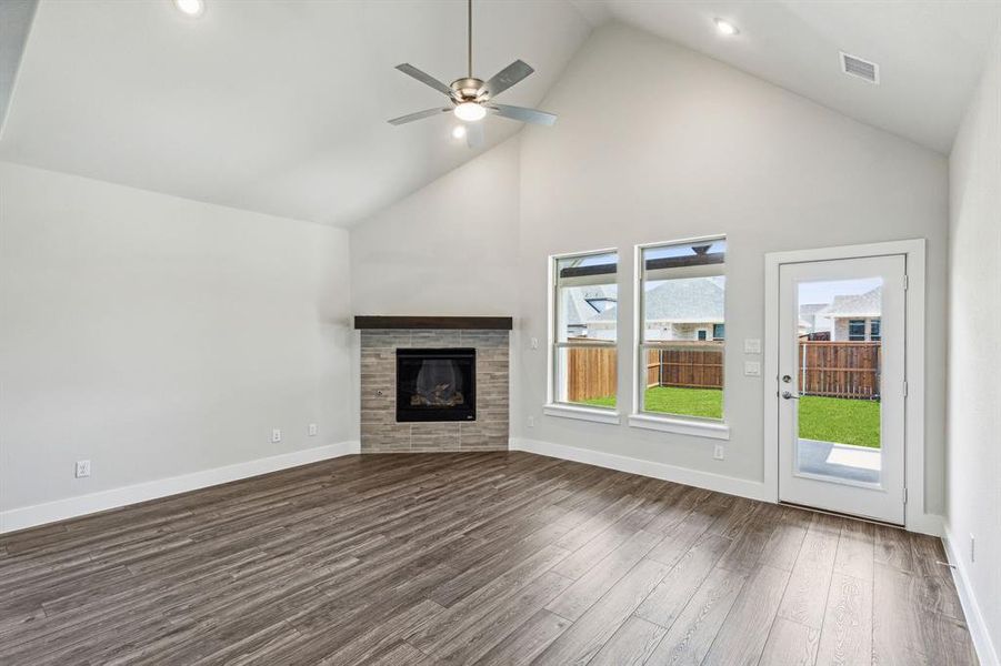 Unfurnished living room with ceiling fan, high vaulted ceiling, and dark hardwood / wood-style flooring