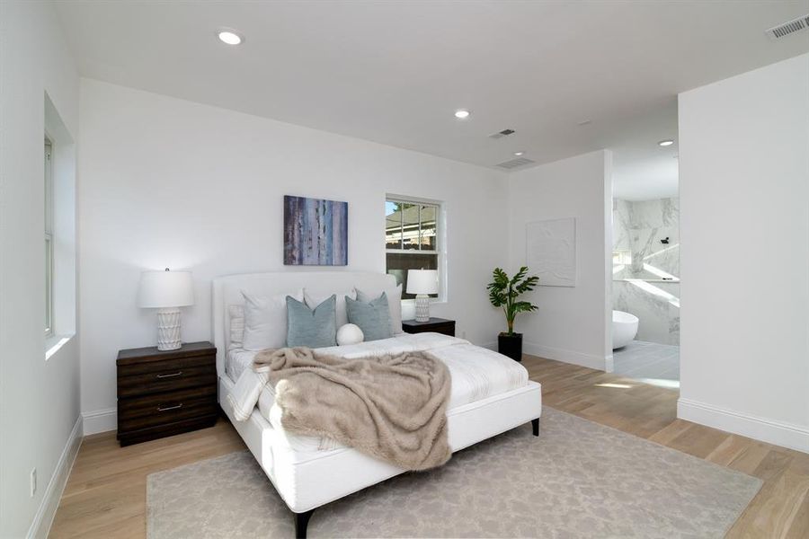 Bedroom with light hardwood / wood-style floors and connected bathroom