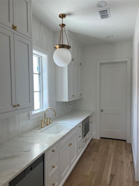 Scullery with second sink, second dishwasher, microwave, brass fixtures and hardware and pendant lighting.