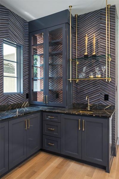 Kitchen featuring sink, dark stone countertops, backsplash, and light hardwood / wood-style flooring