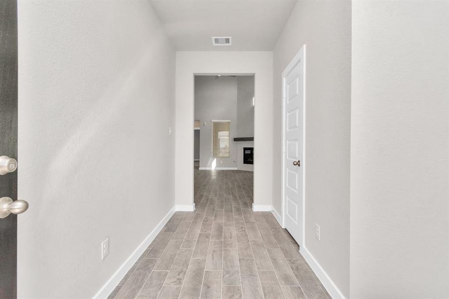 Greeted by a elegant glass front door, the entrance beckons with high ceilings, adorned with elegant wood-look tile flooring and oversized baseboards. Sample photo of completed home with similar floor plan. As-built interior colors and selections may vary.