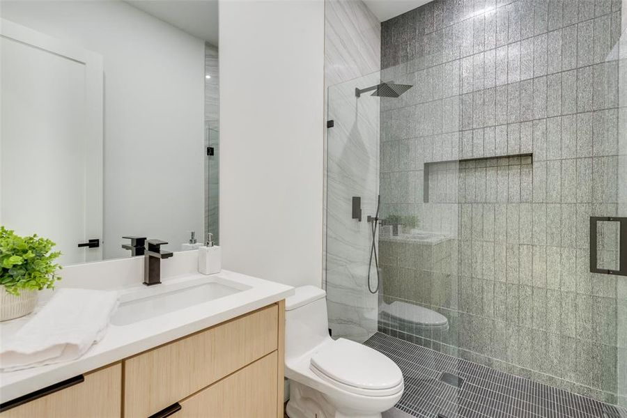 Bathroom featuring an enclosed shower, vanity, and toilet