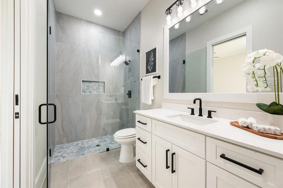 Bathroom featuring vanity, toilet, tile patterned flooring, and a shower with door