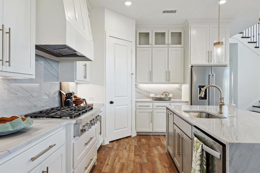 Kitchen with tasteful backsplash, stainless steel appliances, light wood-type flooring, custom range hood, and white cabinets