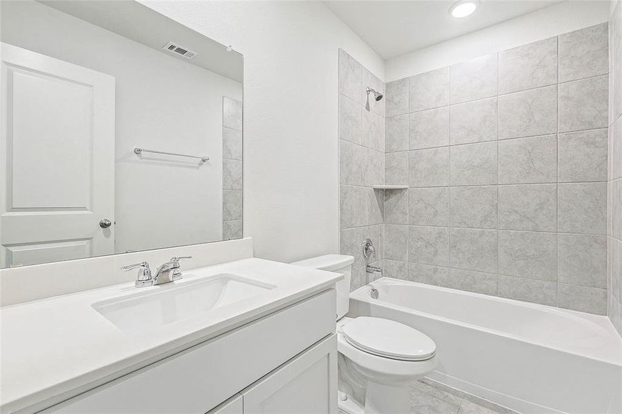 Full bathroom featuring vanity, tiled shower / bath, tile patterned floors, and toilet