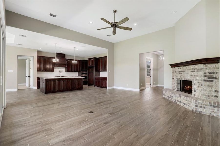 Unfurnished living room featuring light hardwood / wood-style floors, sink, a brick fireplace, and ceiling fan