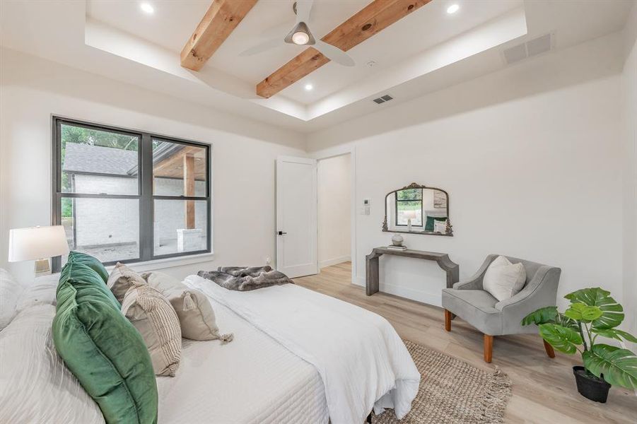 Bedroom featuring a tray ceiling, ceiling fan, and blonde plank, wood-like luxury vinyl floors.