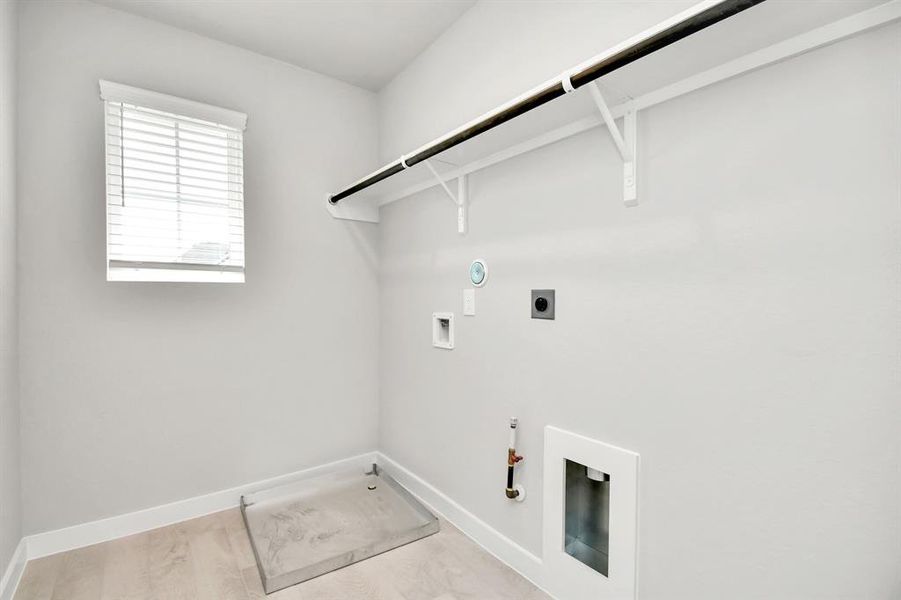 A spacious utility room with ample shelving for organization. It features connections for both gas and electric dryers, making it versatile and functional for all laundry needs. Sample photo of completed home with similar floor plan. Actual colors and selections may vary.