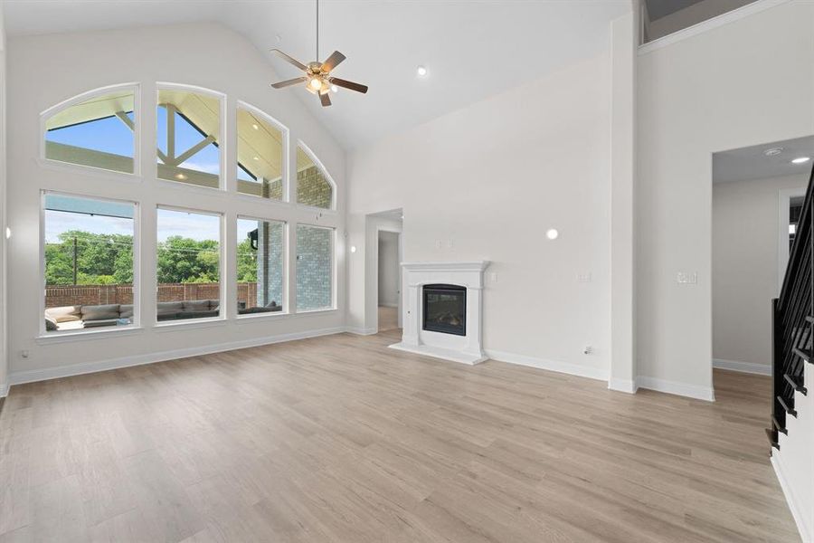 Unfurnished living room featuring light hardwood / wood-style floors, high vaulted ceiling, and ceiling fan