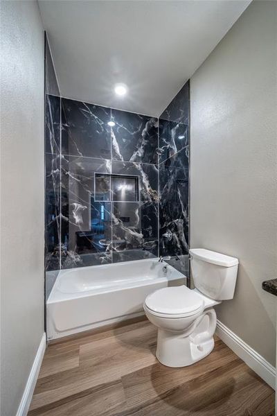 Bathroom with toilet, hardwood / wood-style flooring, and tiled shower / bath