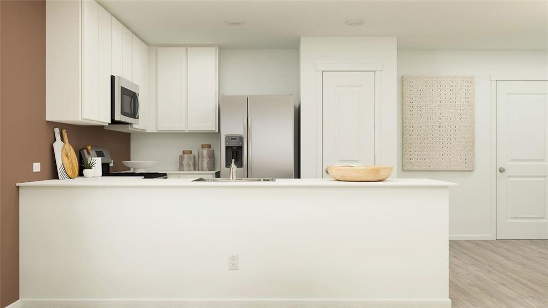 Kitchen with kitchen peninsula, light hardwood / wood-style floors, stainless steel appliances, and white cabinets