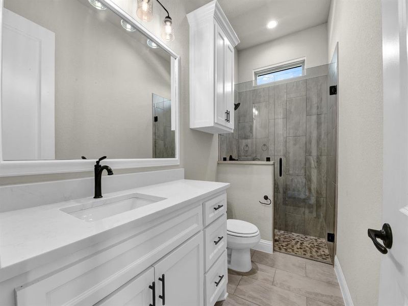 Bathroom featuring an enclosed shower, tile patterned floors, toilet, and vanity