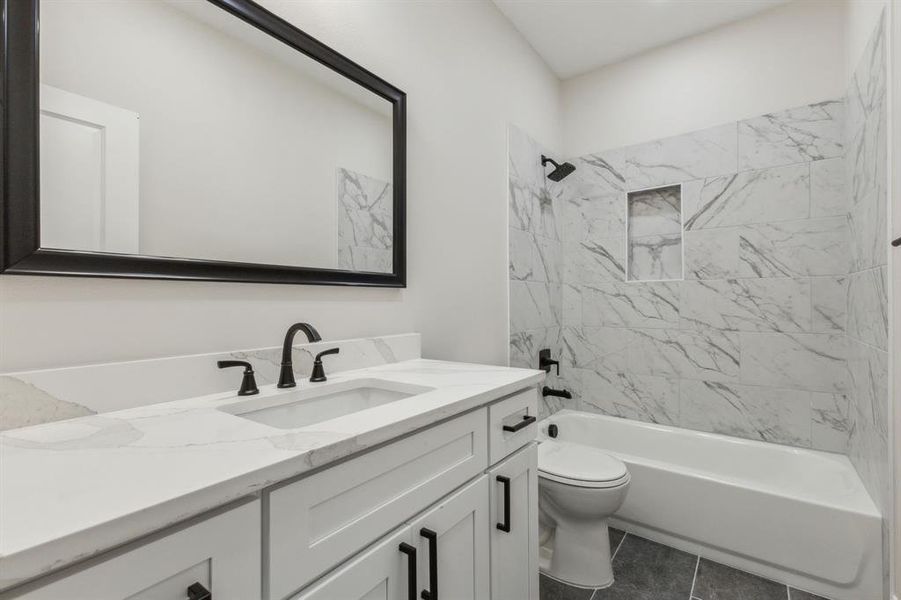 Full bathroom featuring tiled shower / bath, vanity, toilet, and tile patterned floors