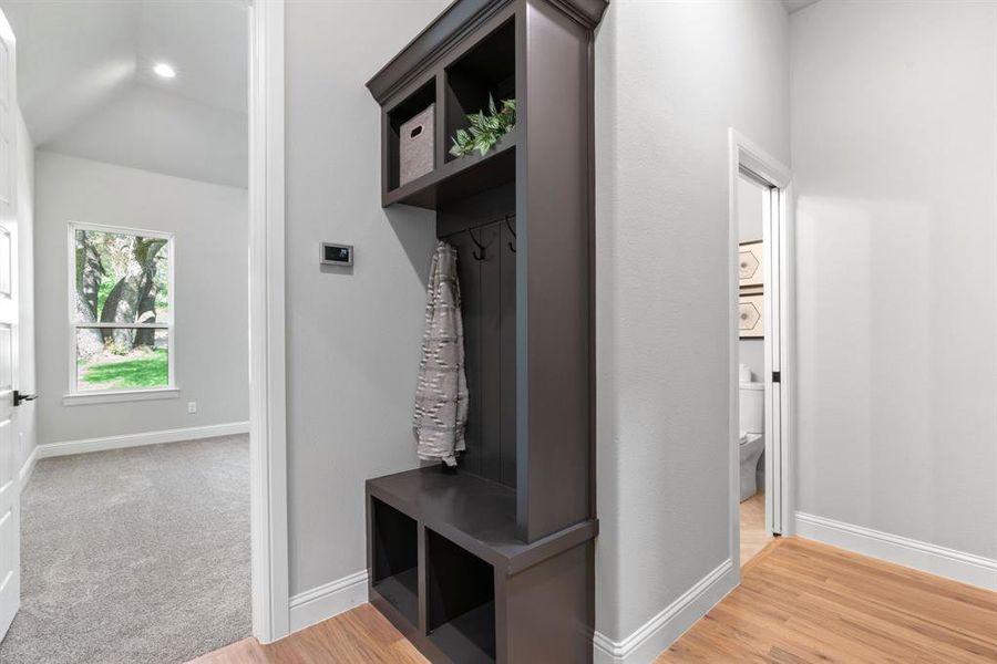 Mudroom with light hardwood / wood-style floors and vaulted ceiling