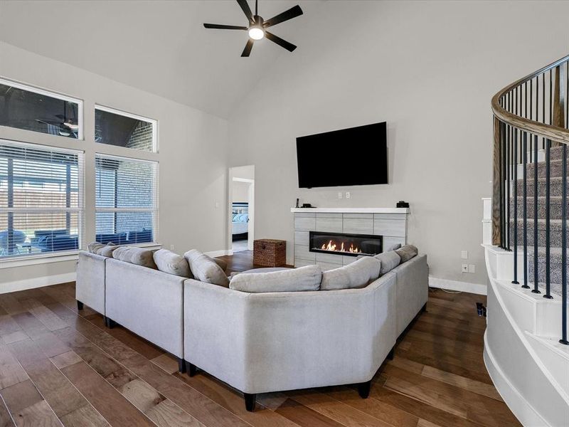 Living room with ceiling fan, high vaulted ceiling, dark hardwood / wood-style flooring, and a fireplace