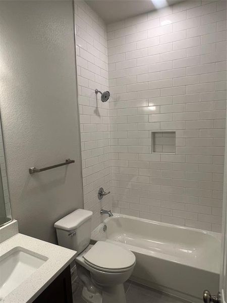 Full bathroom featuring tiled shower / bath combo, vanity, and toilet