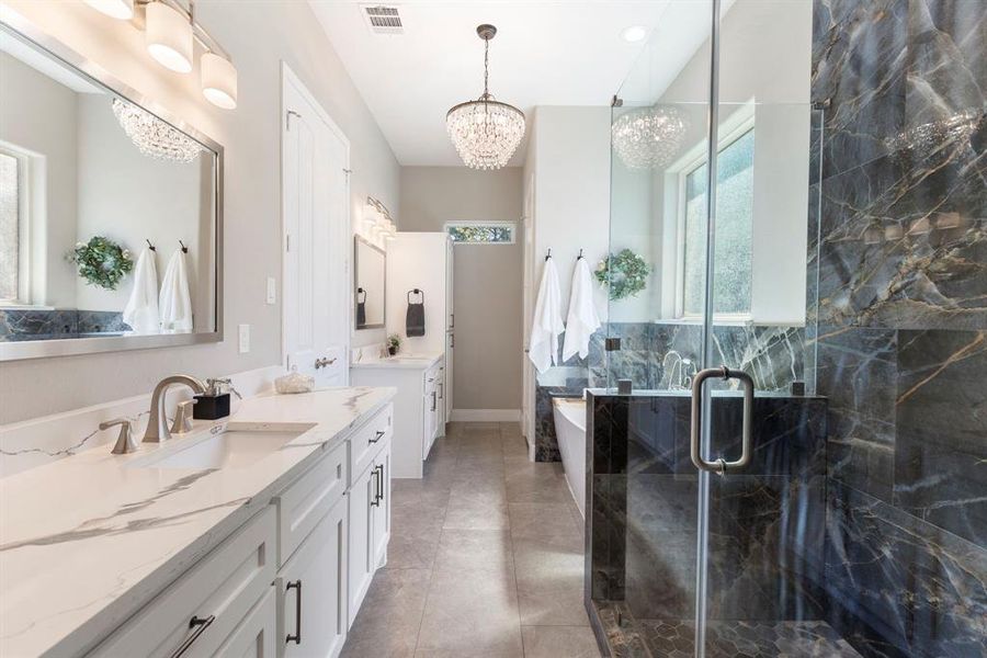 Wow! This primary bathroom has it all! Extra large countertop (for her) with plenty of drawer space, a second sink (for him) with storage space, large walk-in frameless shower with rain shower head/wand feature, designer tile finishes throughout, and chandelier lighting.