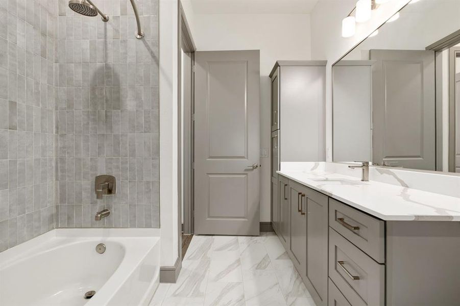 Bathroom featuring tile floors, tiled shower / bath combo, and vanity with extensive cabinet space