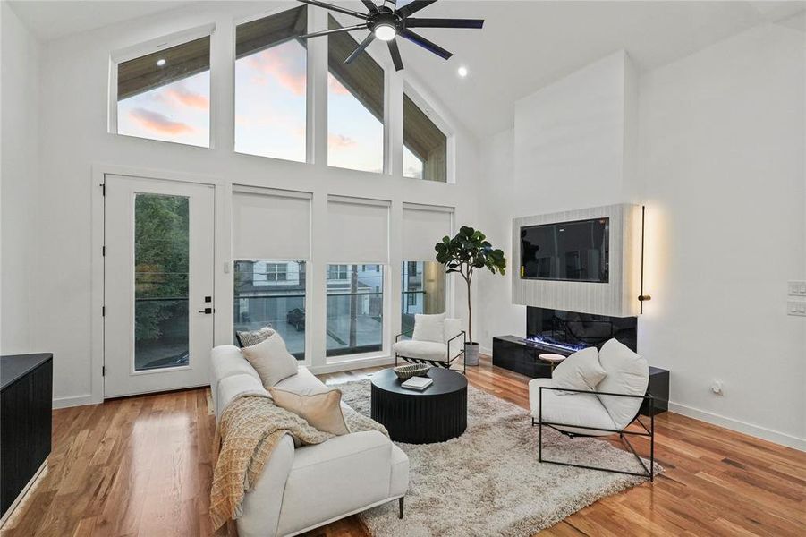 Living room with high vaulted ceiling, ceiling fan, and light hardwood / wood-style flooring