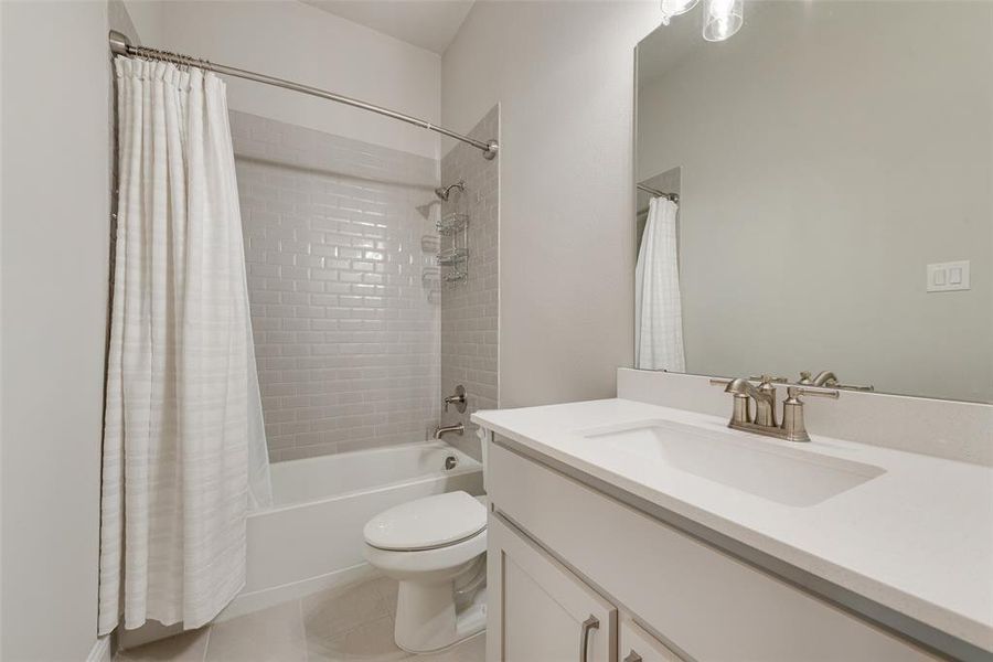 Full bathroom featuring shower / tub combo, tile patterned floors, vanity, and toilet