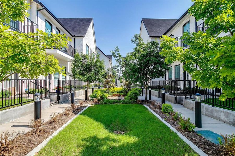 The community area is beautifully landscaped, featuring lush greenery, vibrant flower beds, and well-manicured lawns.