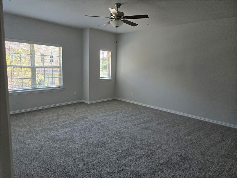 Carpeted spare room featuring ceiling fan and plenty of natural light