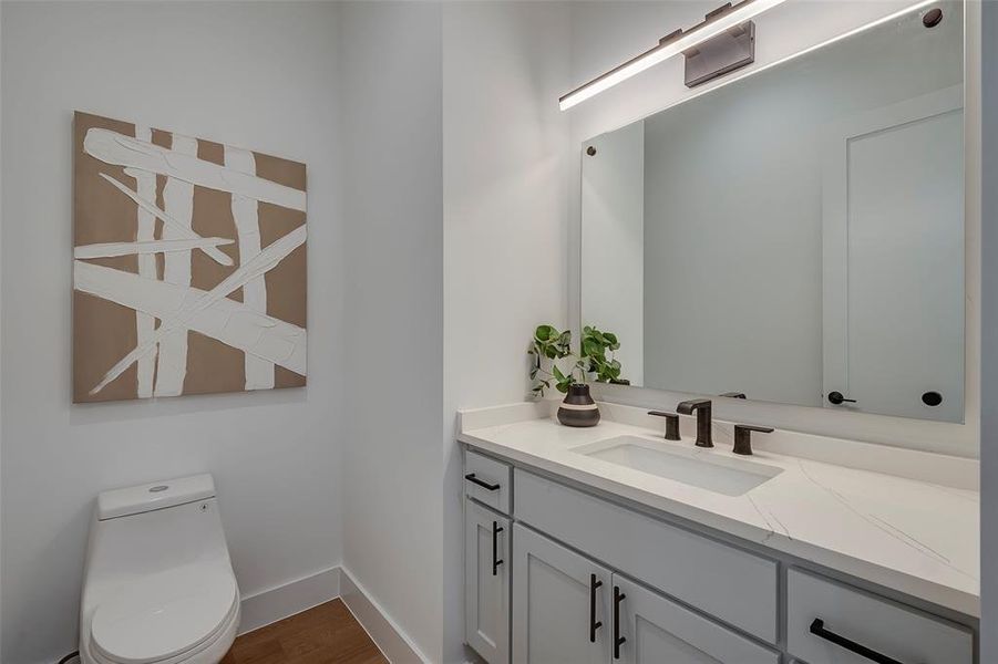 Powder Bathroom with hardwood / wood-style floors, toilet, and vanity