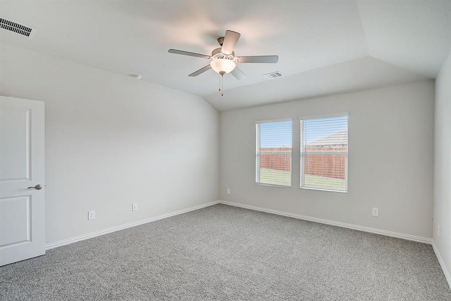 Carpeted empty room featuring vaulted ceiling and ceiling fan