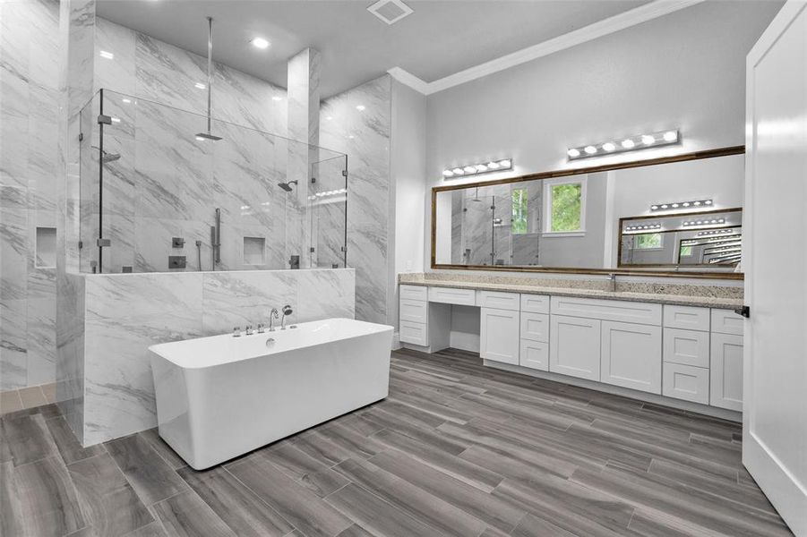 A freestanding tub offers a variety of faucets, while the walk-through shower offers a rain shower, along with wall and handheld shower heads. Dual vanities with Delta sinks and hardware.