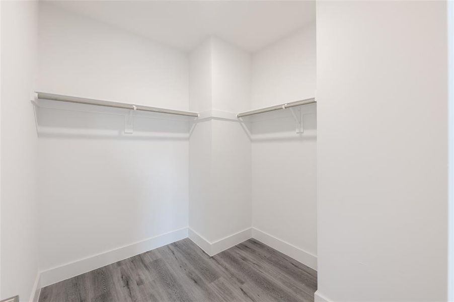 *Representative Photo. Primary Bedroom walk-in closet with ample hanging space, featuring modern gray flooring. Perfect for organizing clothing and accessories.