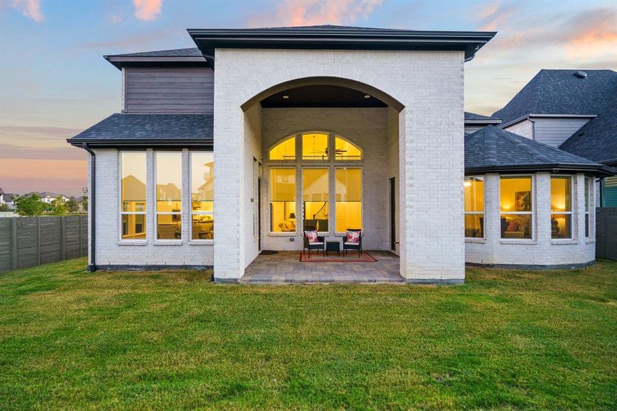 Back house at dusk with a patio and a yard