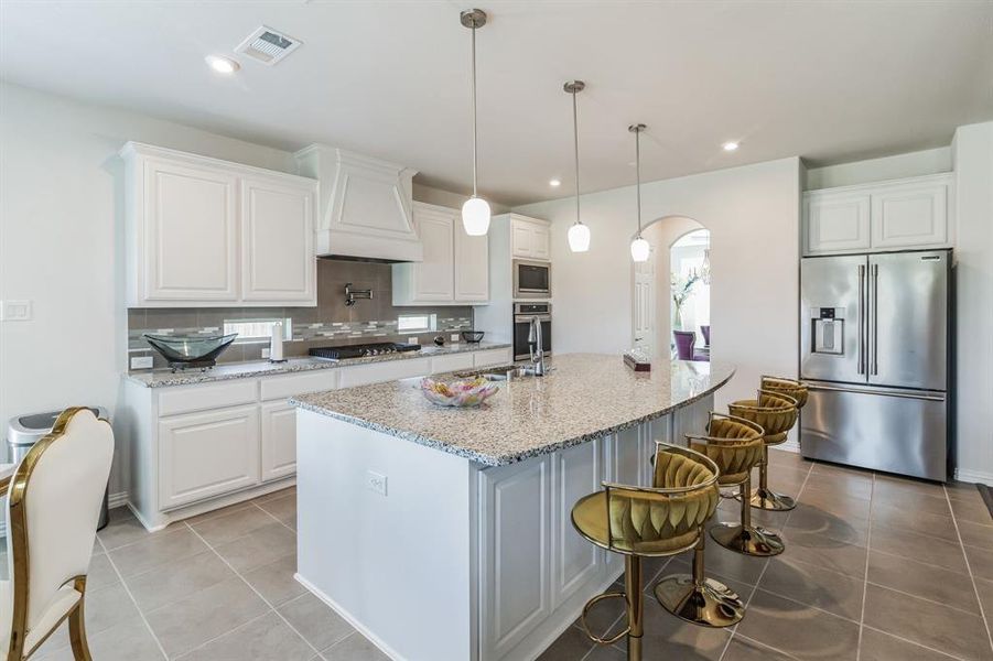 Kitchen featuring white cabinetry, custom exhaust hood, and stainless steel appliances