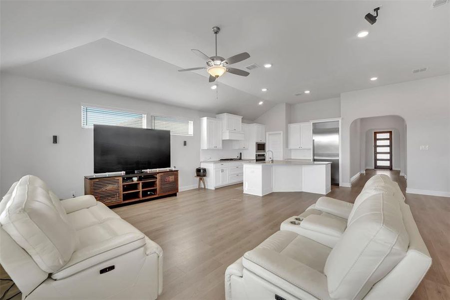 Living room featuring ceiling fan, light hardwood / wood-style floors, and vaulted ceiling