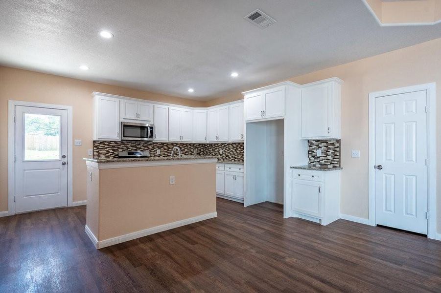 Kitchen featuring dark hardwood / wood-style flooring, white cabinets, and backsplash