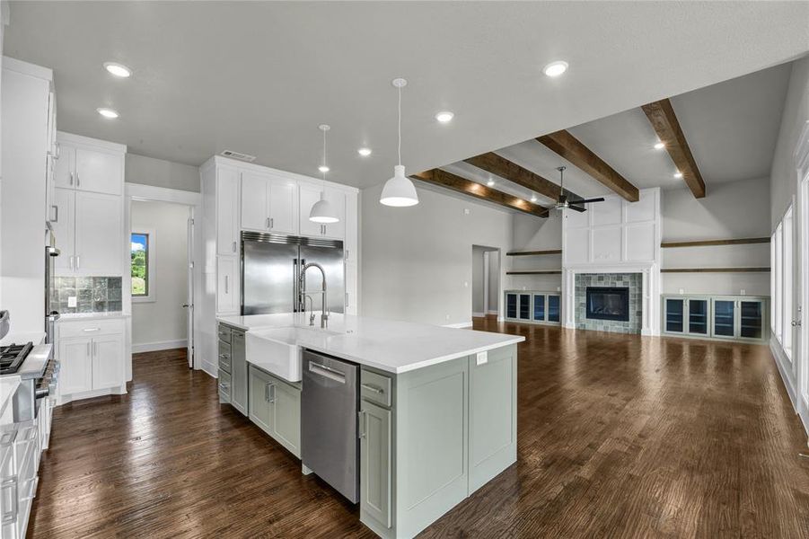 Kitchen with beam ceiling, decorative light fixtures, a kitchen island with sink, and stainless steel appliances
